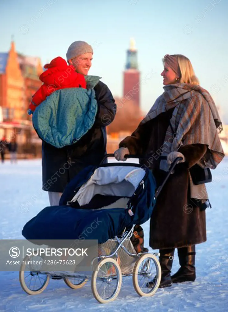 Family pushing baby carriage across frozen Riddarfjarden in Stockholm winter
