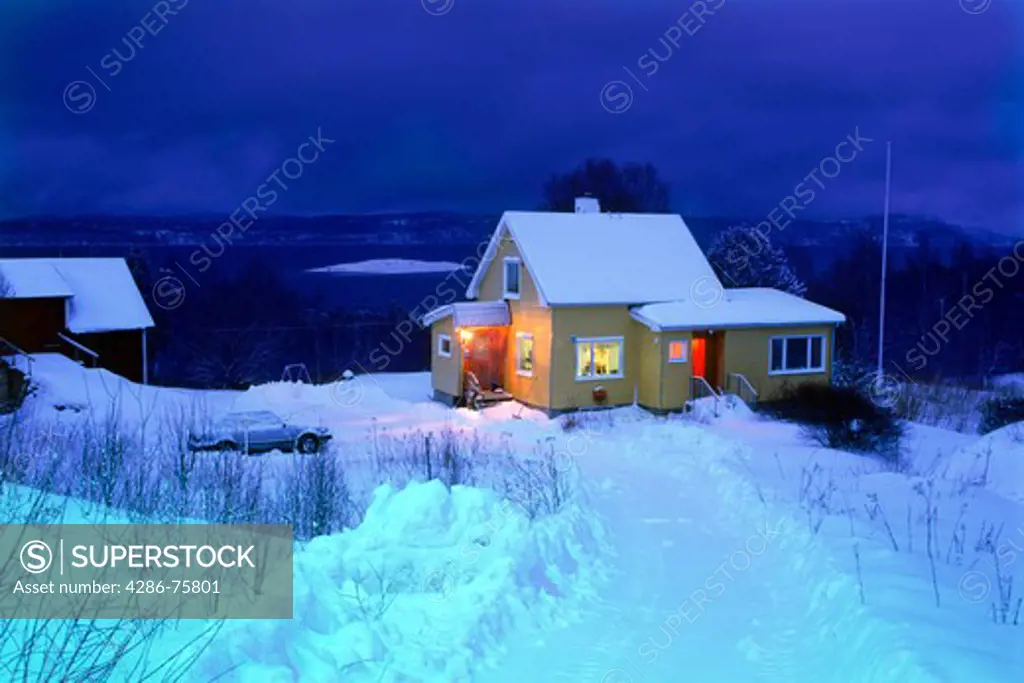 Evening lights from snowbound home on long winter night in Lofoten Islands