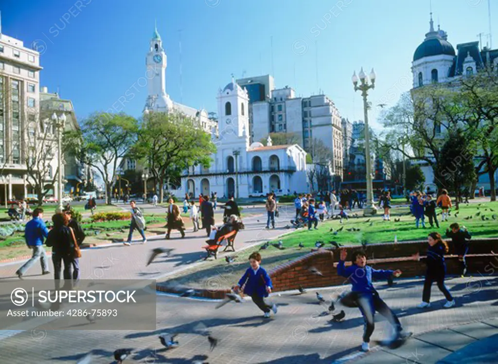 The Cabildo and Clock Tower above playful children and pigeons at Plaza de Mayo in Buenos Aires