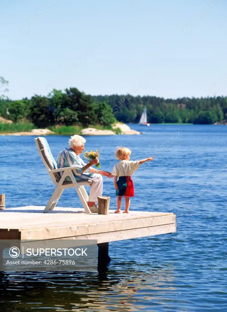 Grandmother with grandson on summerhouse dock in Stockholm Archipelago
