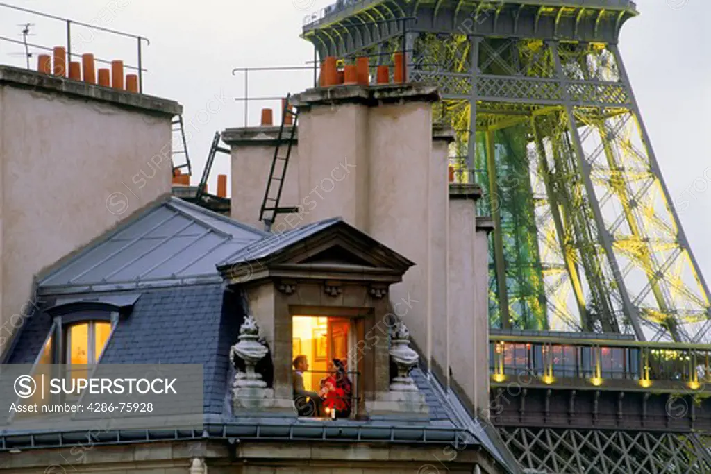Couple in Paris apartment sharing evening drink with Eiffel Tower behind