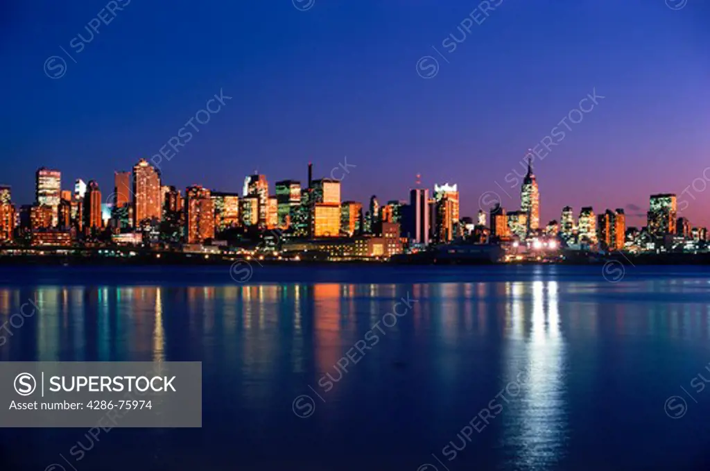 New York City skyline with Empire State Building reflecting off Hudson River from New Jersey at dusk