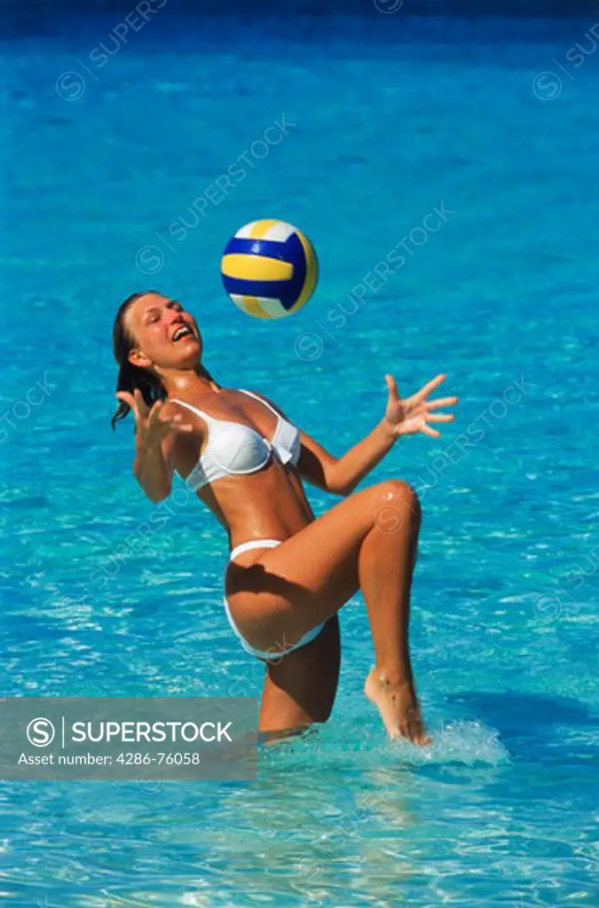 Woman playing with beachball in shallow water