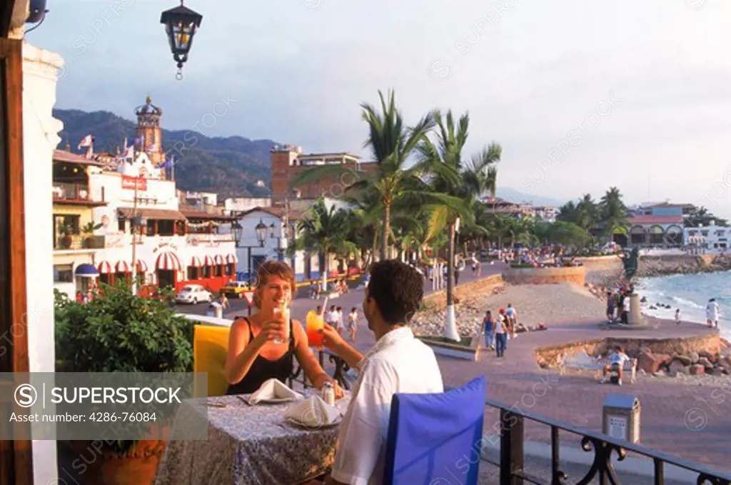 Couple having sunset drinks at oceanfront restaurant in Puerto Vallarta Mexico