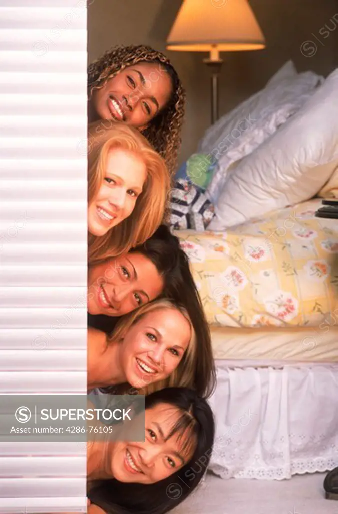 Five women of ethnic mix stacked on top of eachother looking out bedroom door