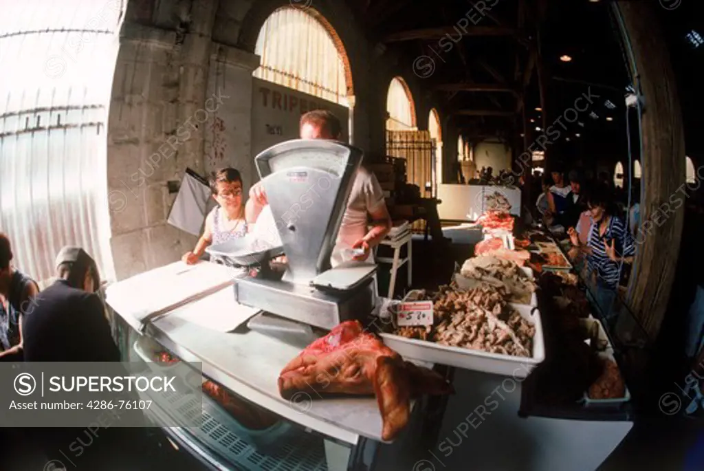 Pigs head with weight scale in open air market with French cheese, vegetables and meats all across France