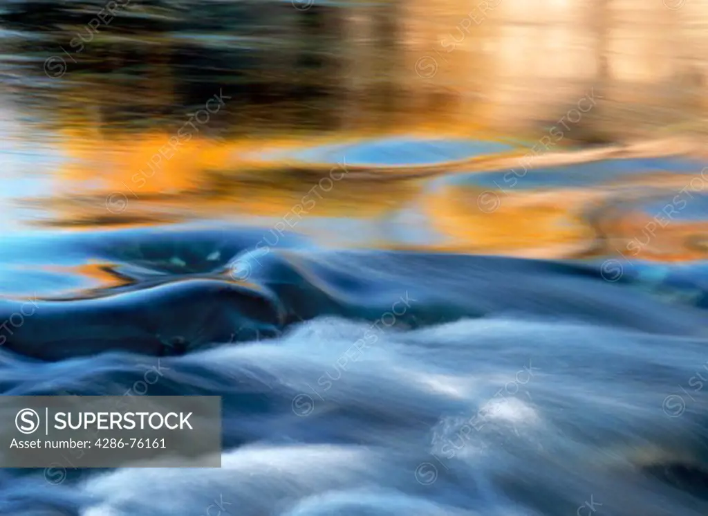 Autumn colors and blue sky reflecting off river with small rapids in Arctic wilderness in Sweden