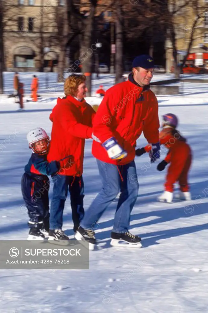Family of three ice skating together on small lake