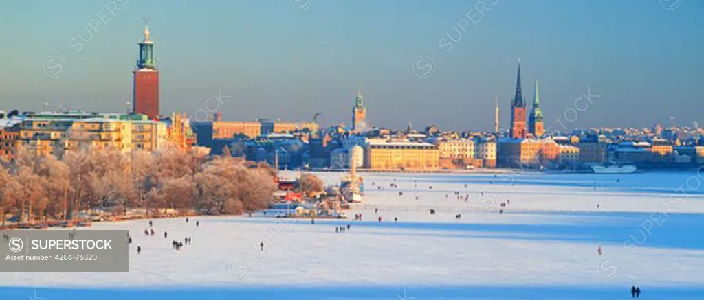 Panoramic image of people strolling across frozen Riddarfjarden toward Riddarholmen in Stockholm winter