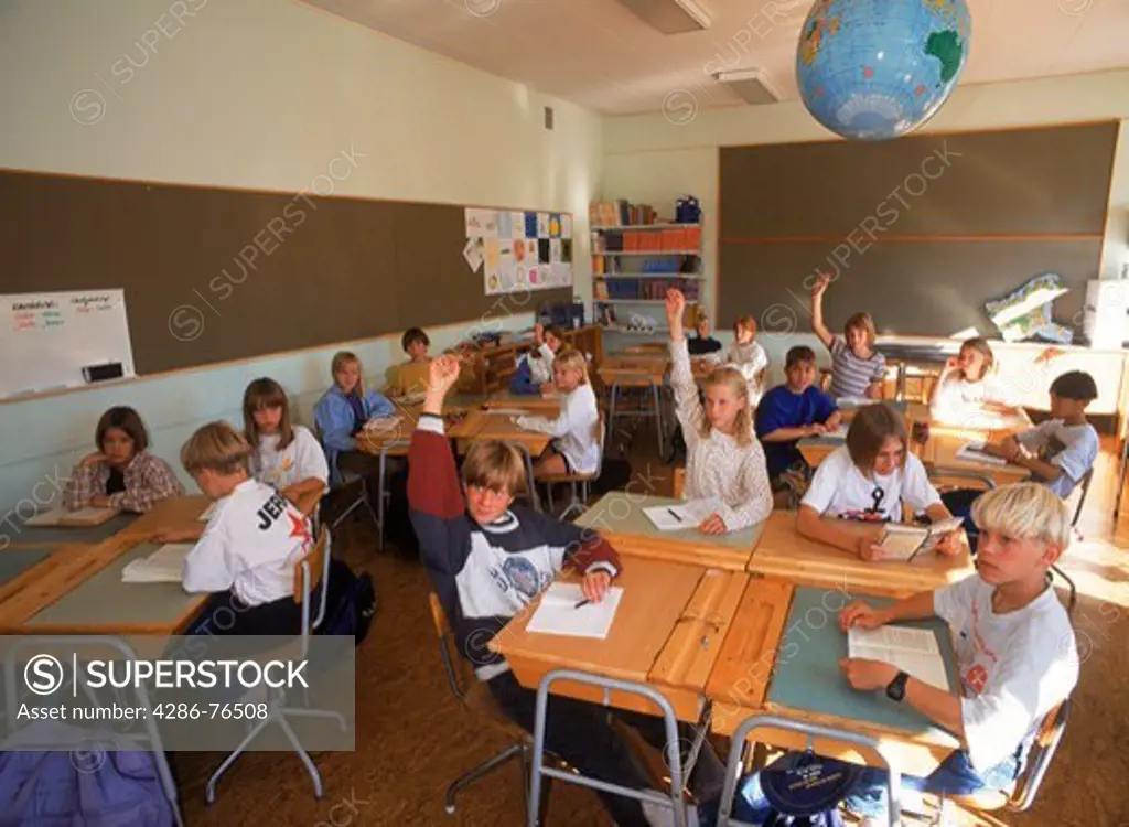 Students in 5th grade Swedish classroom sitting at desks with raised hands during question and answer session