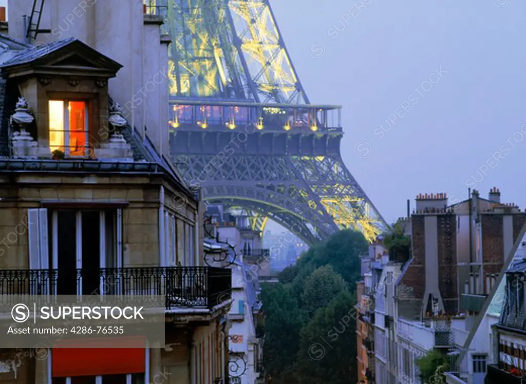 Light in top floor apartment window with Eiffel Tower depicting Paris night life