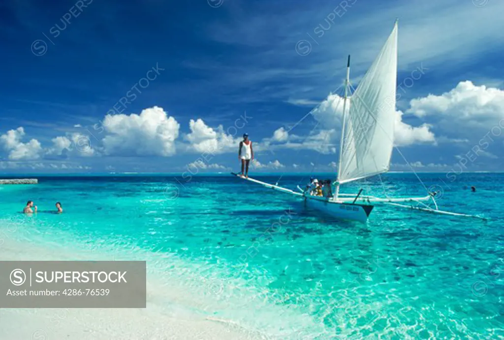 Outrigger canoe sailing with tourists off Island of Bora Bora in French Polynesia