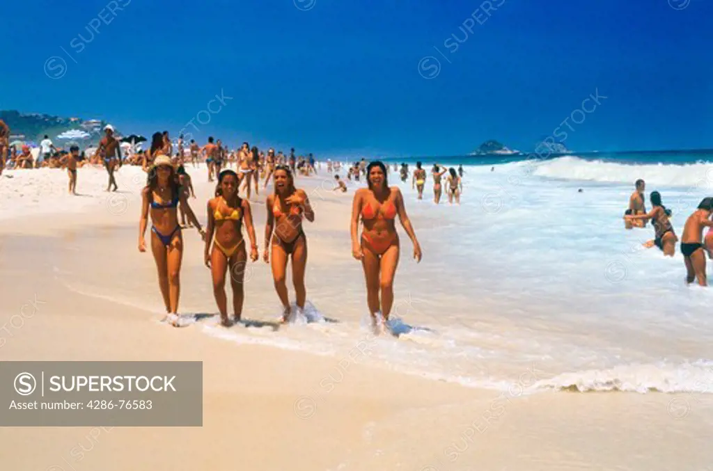 Four young women in bikinis walking along Ipanema Beach in Rio de Janerio
