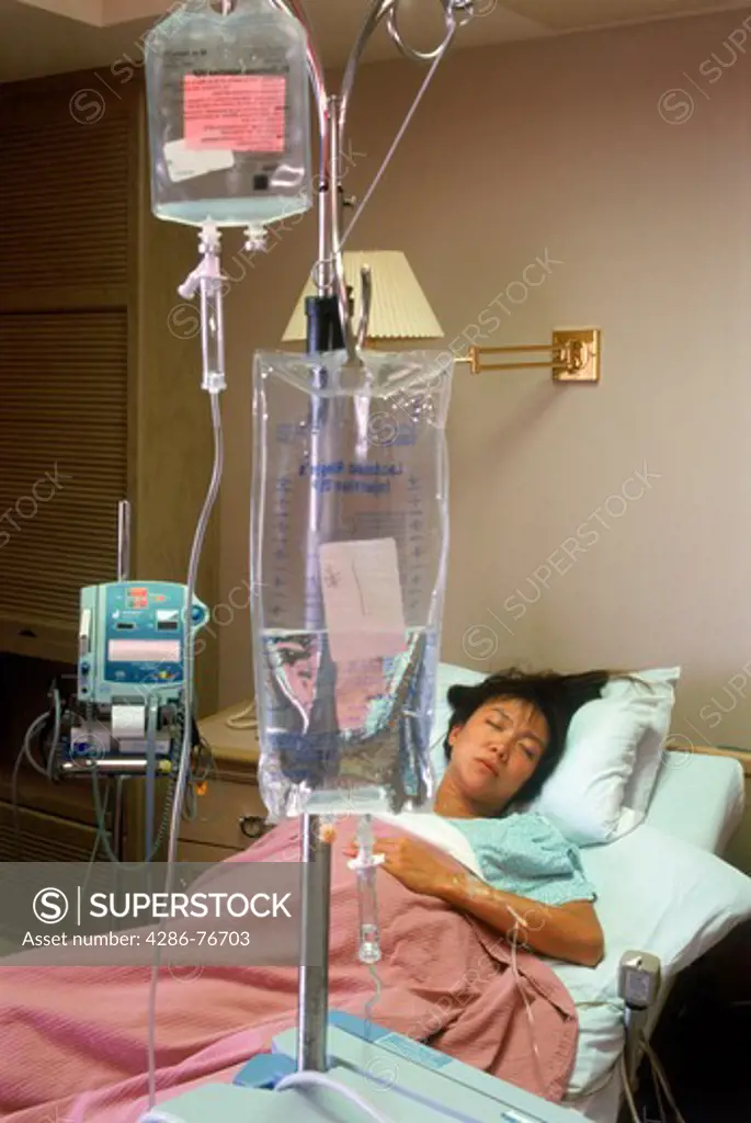 Woman connected to IV tubes in hospital recovery room