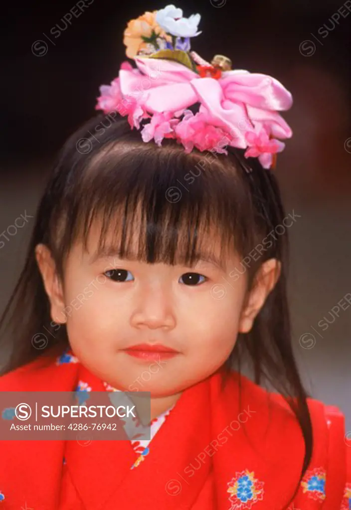 Japanese girl in red kimono robe with flower hair decoration