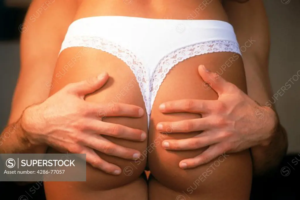Man holding womans buttocks giving girlfriend a rump hug.  Couple in 20s sharing playful romantic fun and sensual moments