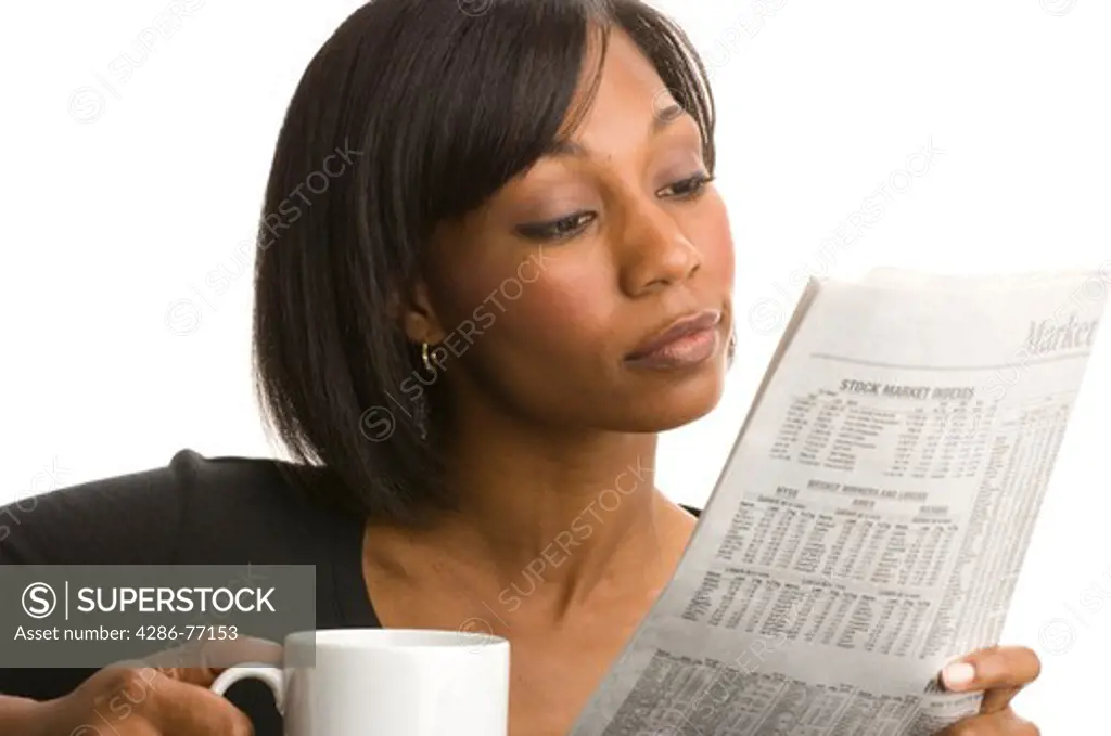 Studio portrait of young African American woman drinking coffee and reading newspaper