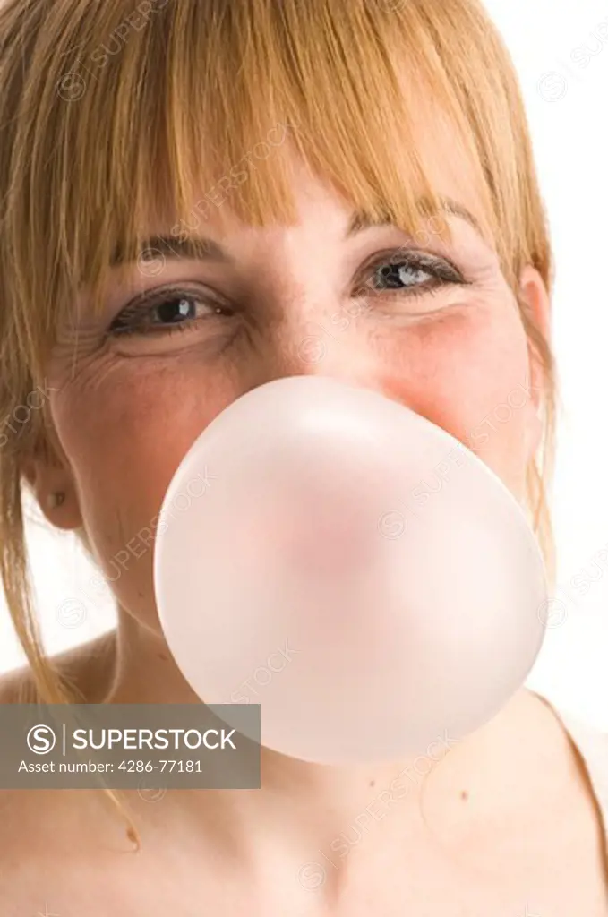 Studio shot of woman blowing pink bubblegum bubble