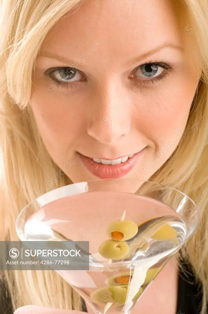 Close-up of an attractive blonde woman sipping on a glass of martini