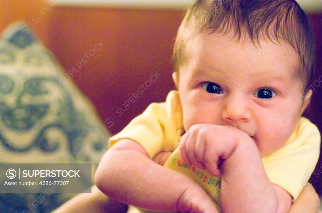 Close up of a baby girl covering her mouth with her arm