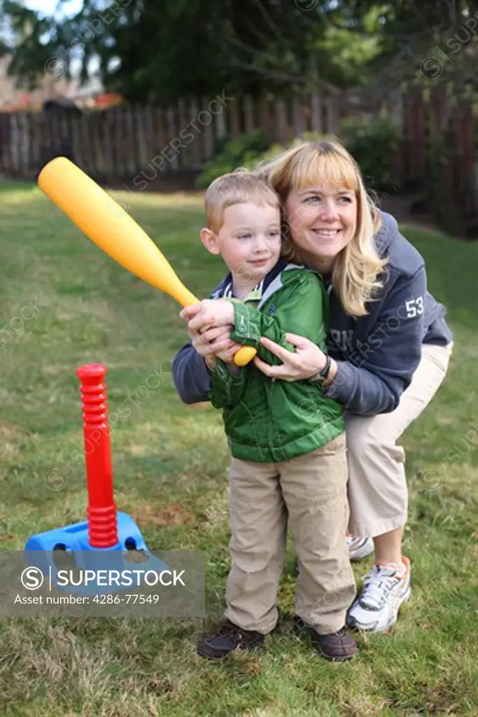 Mother helping young son swing a plastic baseball bat
