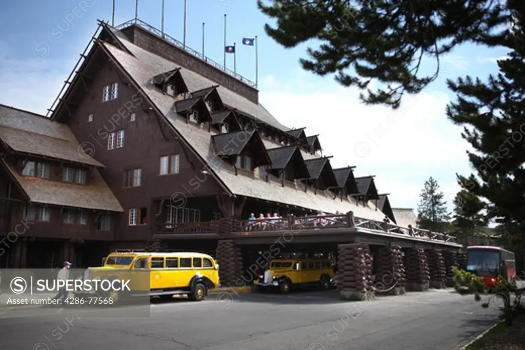 A restored vintage Yellowstone Park tour bus in front of Old Faithful Inn