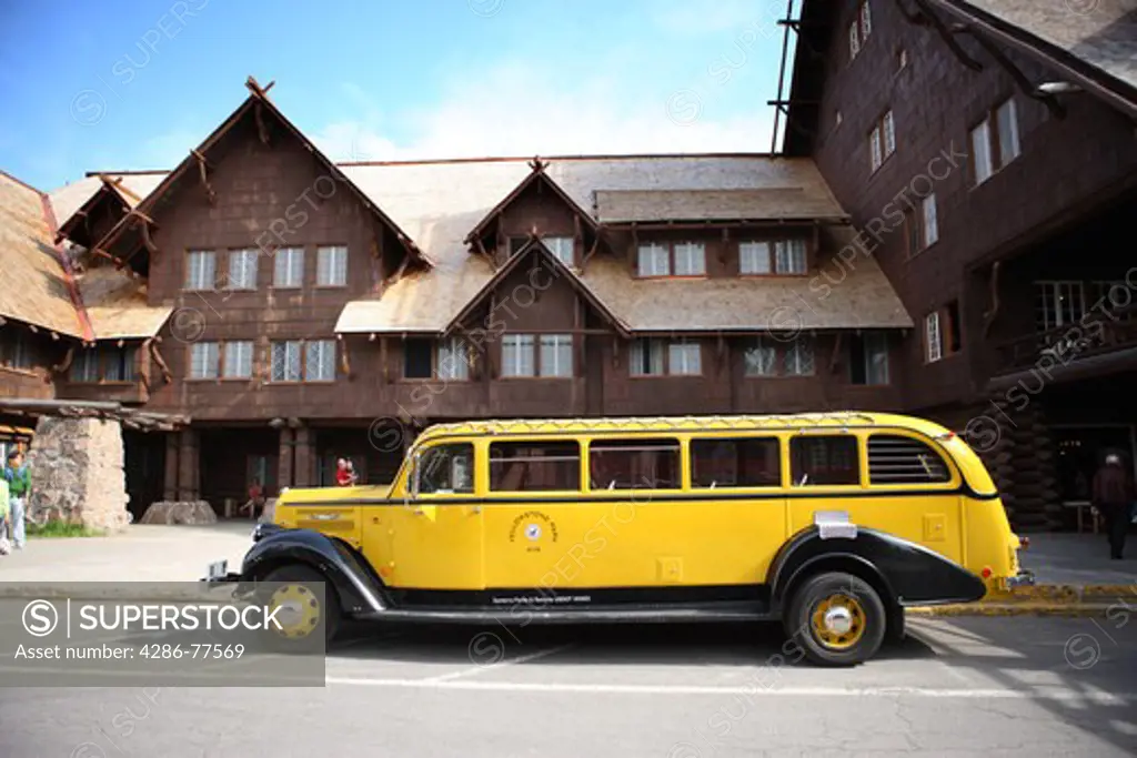 A restored vintage Yellowstone Park tour bus in front of Old Faithful Inn