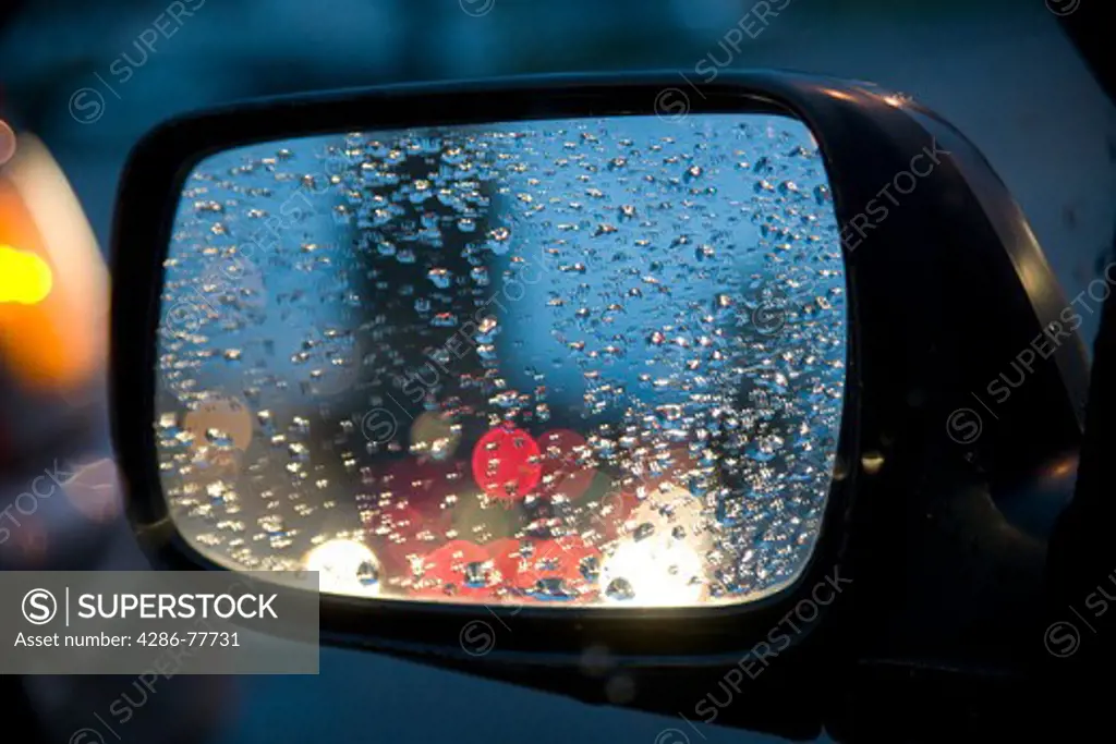 Rain drops on the side view mirror of a car
