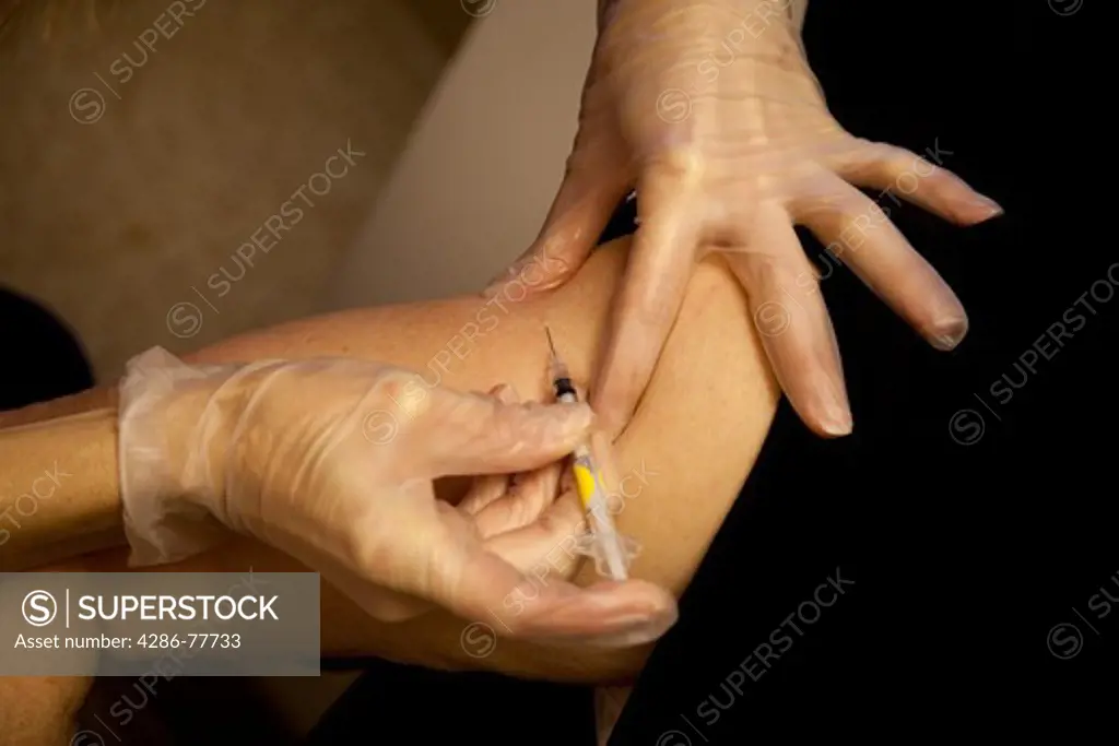 Close up of hands wearing protective gloves injecting an arm