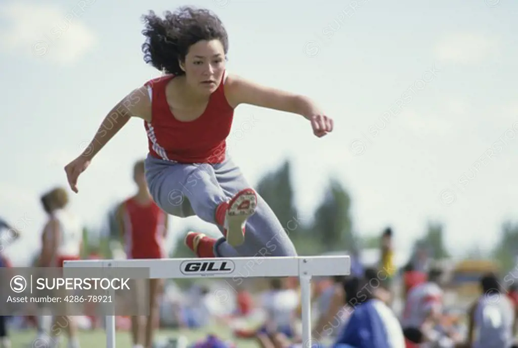 Young Hispanic woman warms up for Women's Low Hurdle race High School Senior, New Mexico State AA Track & Field