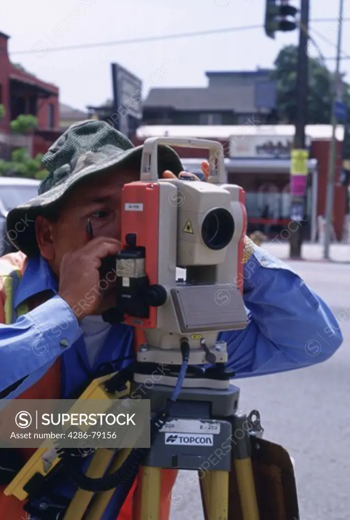 Worker using Electronic Distance Measuring machine  for street construction project, Hollywood, California