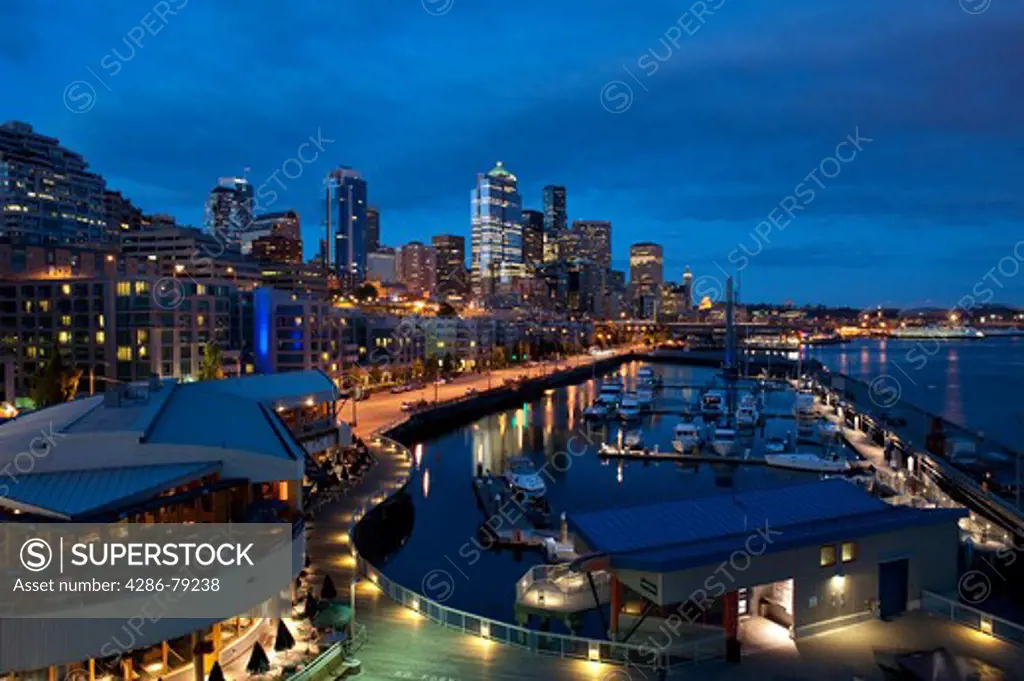 Seattle skyline and Pier 66 illuminated at sunset with tourists sightseeing along the Seattle waterfront, Washington State USA