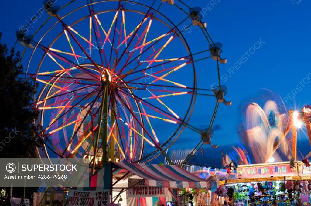 Evergreen State Fair at twilight with Ferris Wheel and amusement rides and game booths at night Monroe Washington State USA