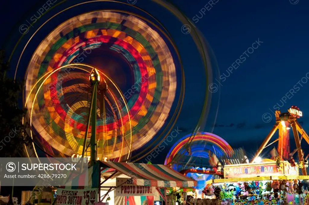 Evergreen State Fair at twilight with Ferris Wheel and amusement rides and game booths at night Monroe Washington State USA