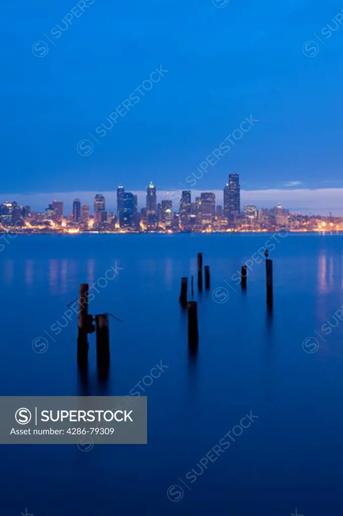 Seattle skyline from West Seattle at sunrise with silhoutetted pilings along Elliott Bay shoreline Seattle Washington State USA