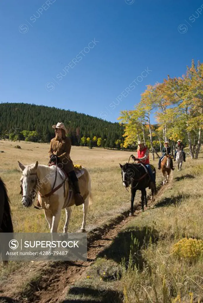 Family group outdoors on a crisp and cool fall morning riding horses in Rocky Mountain National Park, near Estes Park, Colorado, USA