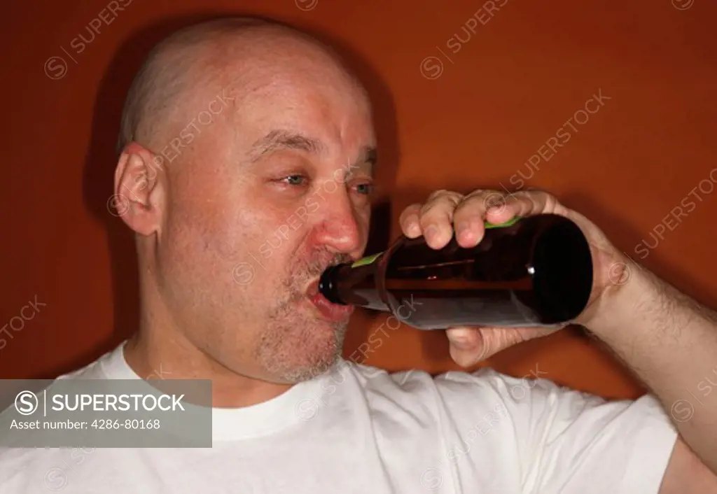 A drunken man drinks a bottle of beer. 