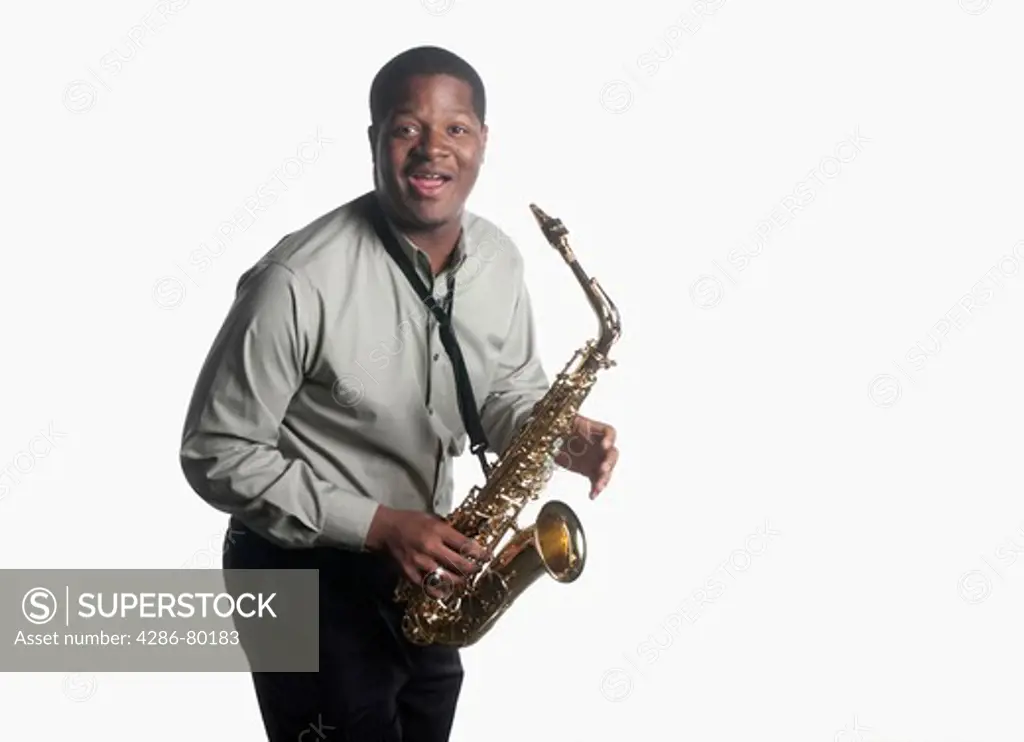 A college age man holds his saxophone and looks surprised.  