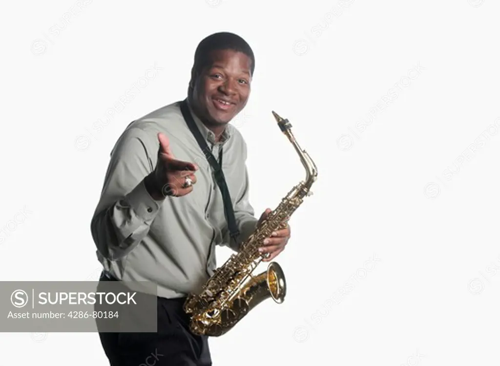 A college age man holds his saxophone and looks confident. 