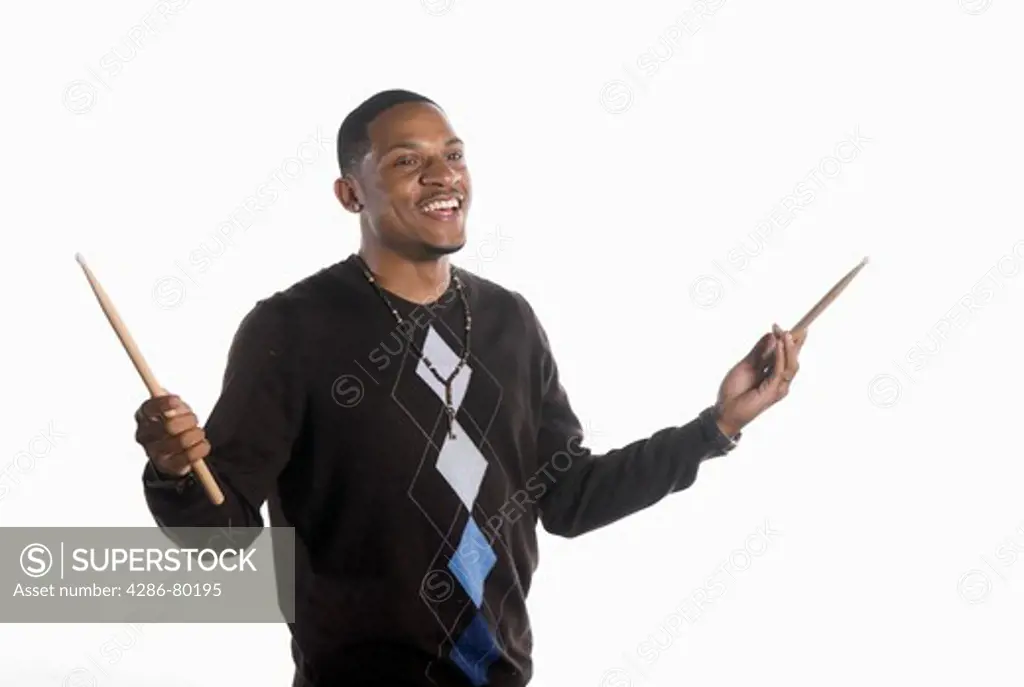 A college age man holds his drum sticks and smiles.
