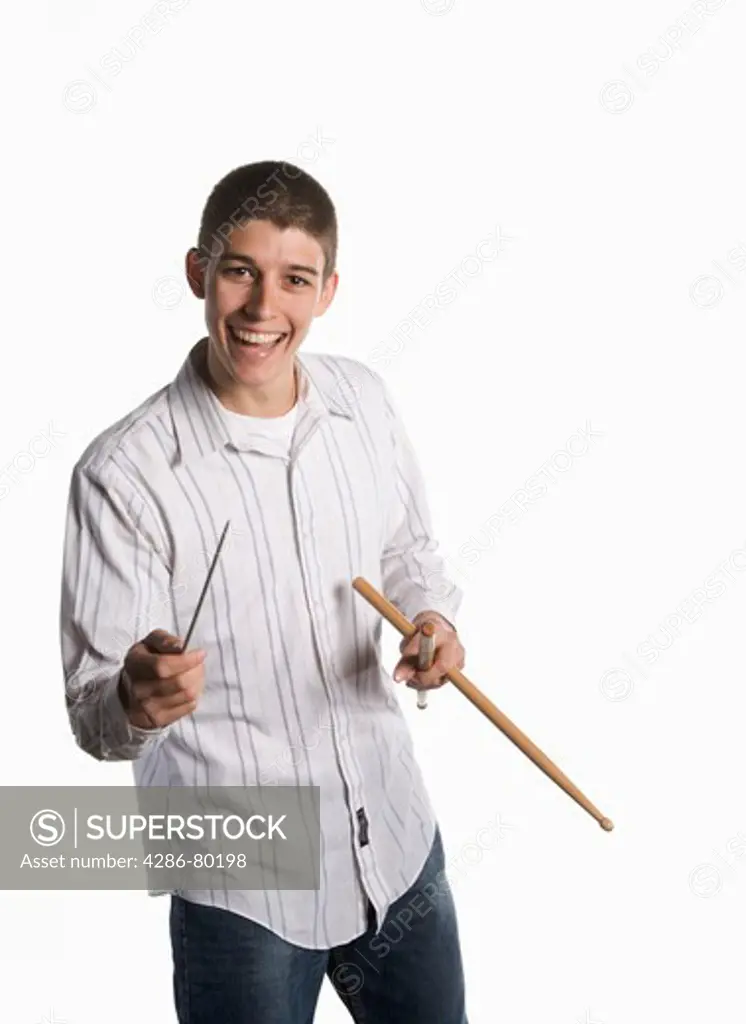 A college age man holds his drum sticks and smiles.