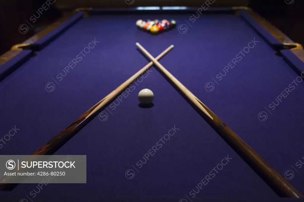 Close-up of pool sticks crossed over on a pool table