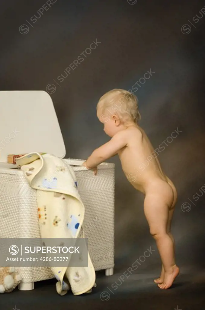toddler naked Portrait of a naked toddler playing in the hamper - SuperStock