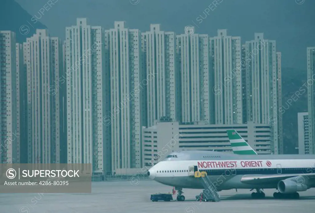 Grounded plane in Hong Kong Airport with subsidized housing in background