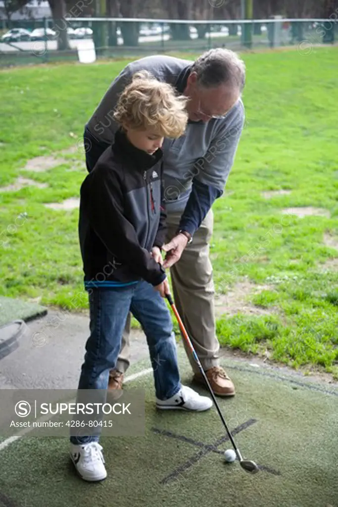 Grandfather teaching golf to grandson