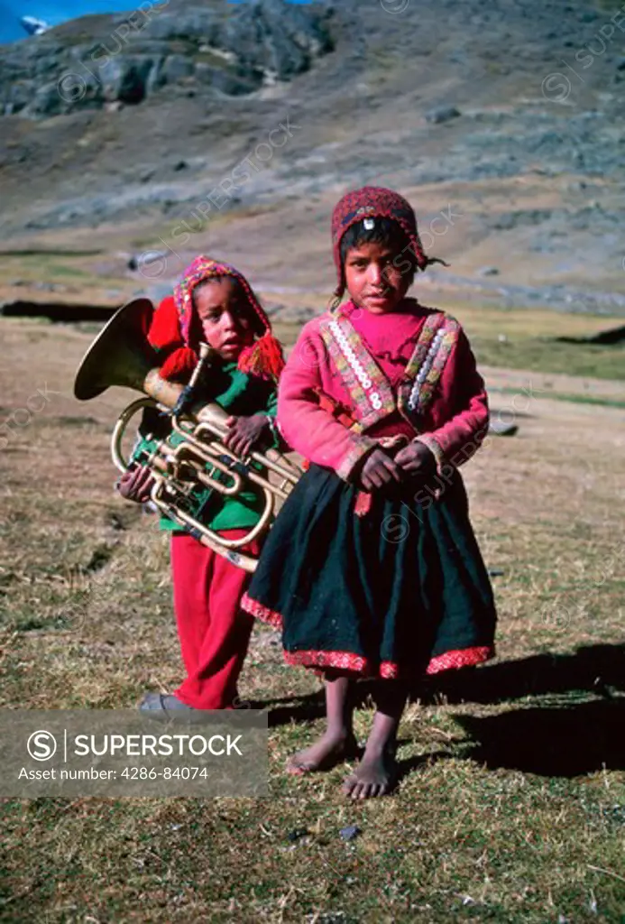 Young Peruvian highland musician and girl dwell at the upper limit of human habitation, 15,000 feet altitude, just under the glaciers of Cerro Ausangate in the Cuzco region's Cordillera Vilcanota.