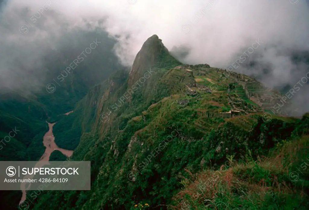 Machu Picchu, lost citadel of the Incas, with its usual noonday shroud of clouds blown up from the nearby Amazon headwater jungle, near Cuzco, Peru.