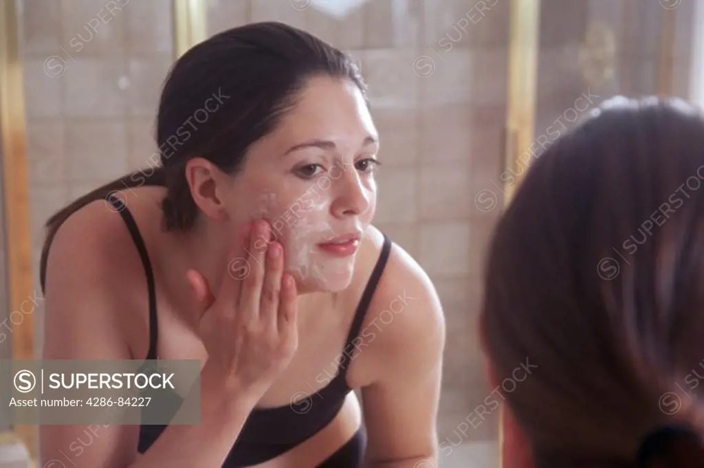 Woman looking into the mirror, washing her face