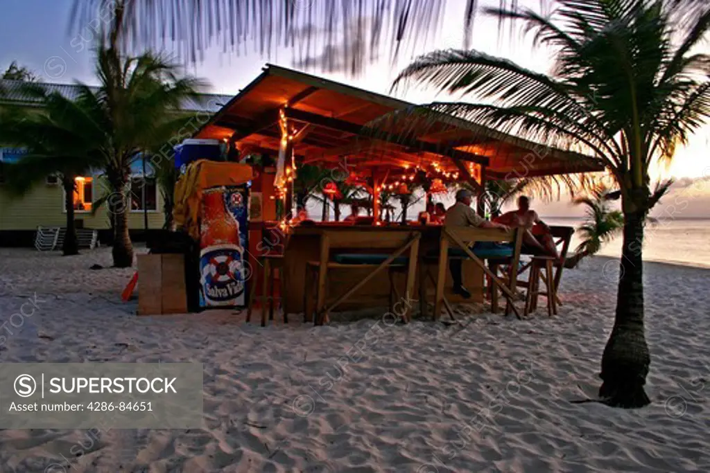 People enjoying cocktails at Infinity Bay Beach Bar, dusk, West Bay Beach, Roatan, Honduras