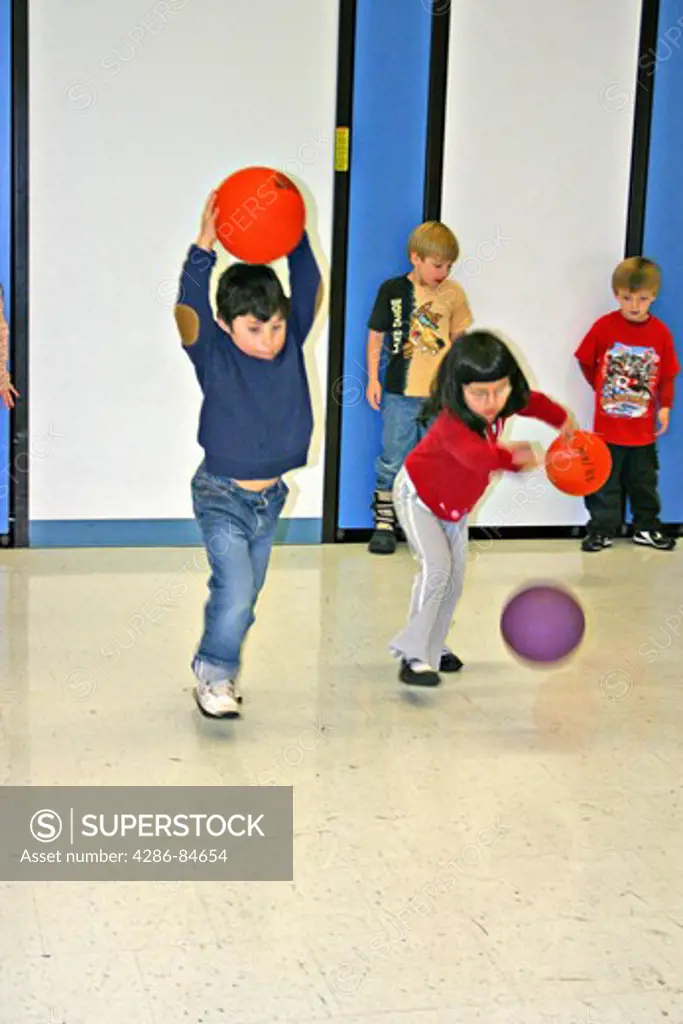 First Grade Mixed ethnic genders students in gym game at elementary school